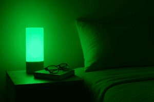 Minimalist room corner softly illuminated by green light, featuring a modern lamp and calming decor elements.